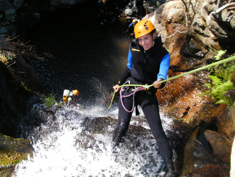 Madeira Tauchen, Surfen: Eine Frau steht angeseilt an einem Felsen im Wasser.