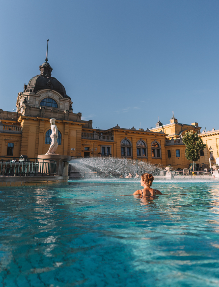 Budapest Städtetrip: Ein Schwimmbad vor einem gelben Gebäude mit einer Person darin.