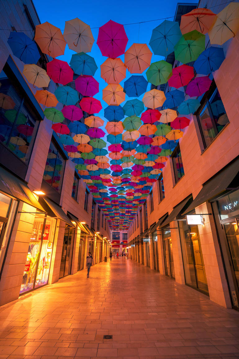 Städtetrip: Die Einkaufsgasse am Abend, mit den bunten Regenschirmen an der Decke.