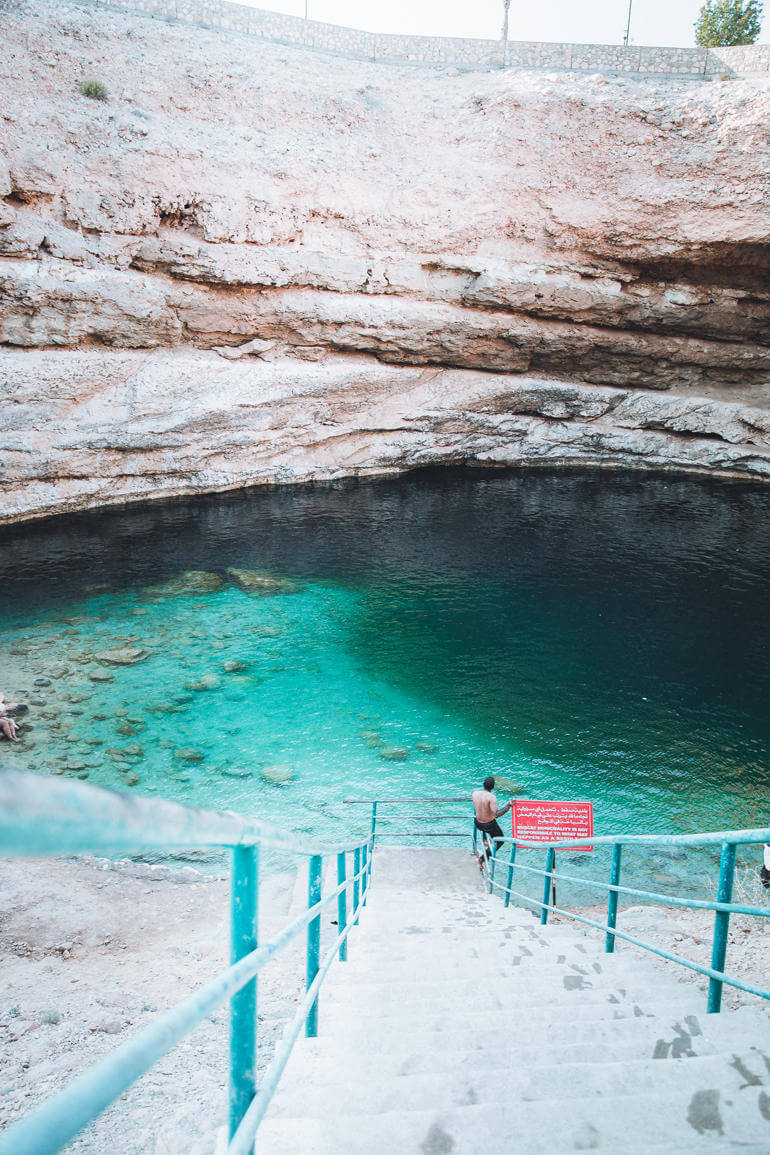 Die steile Treppe des Bimah Sinkhole im Oman führt Besucher zu einer blaugrün-schimmernde Lagune.