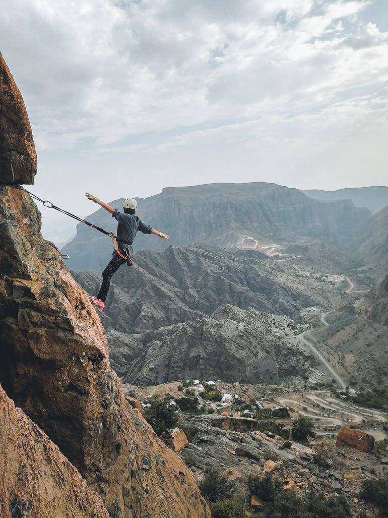 Roadtrip durch den Oman: Eine Frau beim Klettern an einer Felswand.