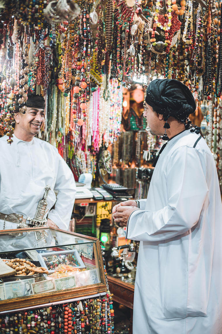 In einem mit über und über Schmuck behängten Laden auf dem Mutrah Souk Markt im Oman unterhalten sich zwei einheimische Männer.
