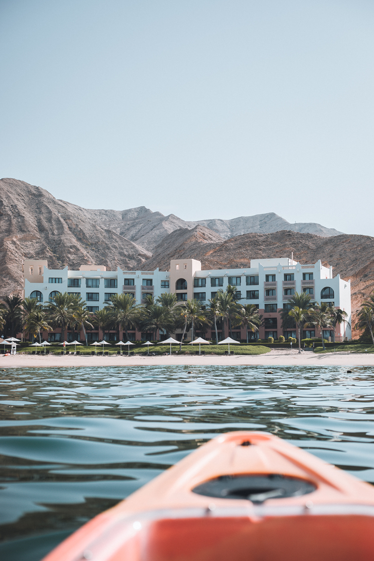 Auf dem Meer vor dem Hotelkomplex des Shangri La Al Bandar im Oman bahnt sich ein oranges Kajak den Weg zum Sandstrand.