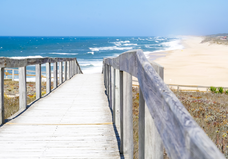 Eine Holzbrücke führt zum Strand von Sao Pedro de Moel, Portugal.