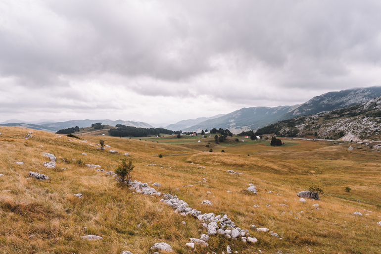 Reisetipps, Geheimtipps, Strand: Eine große Wiese mit Bergen im Hintergrund.