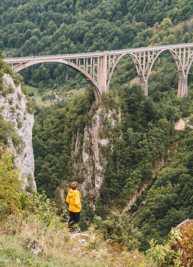 Bloggerin Melanie Schillinger steht am Abhang der Tara-Schlucht und bestaunt aus der Ferne die Brücke, die sie überspannt.