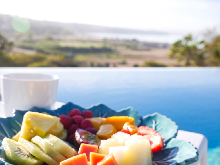 Ein Obstteller und eine Kaffeetasse mit Ausblick auf eine Landschaft.