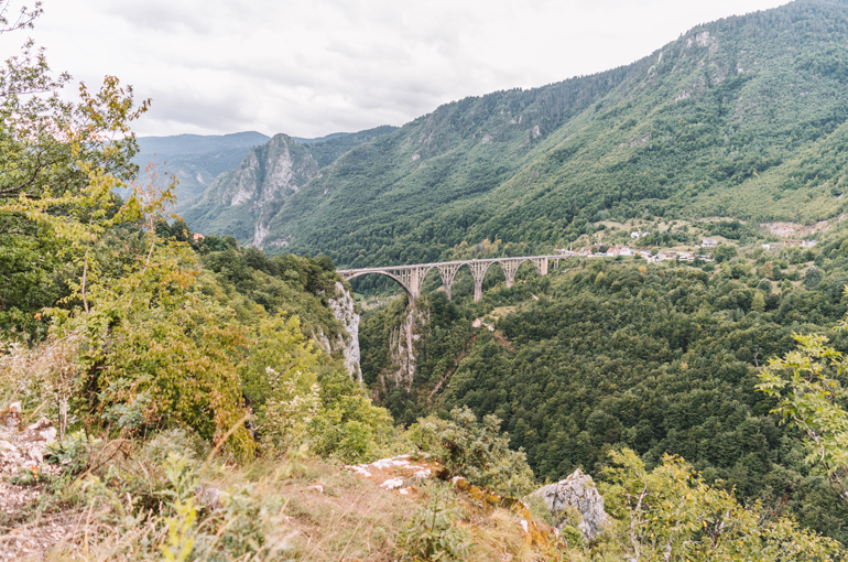 Die runden Bögen der Tara-Brücke erstrecken sich über der Schlucht und verbinden die grün bewaldeten Berge ringsherum.