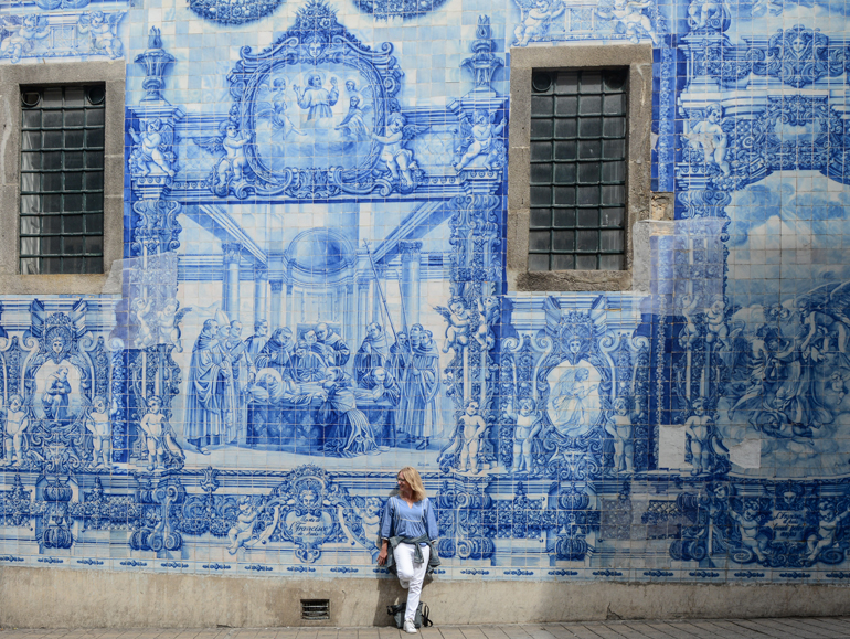 Porto Sehenswürdigkeiten: Eine Wand voller Fließen mit einer Frau davor.