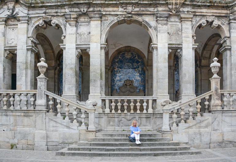 Porto Sehenswürdigkeiten: Eine Frau die vor einem altem Gebäude auf einer Treppe sitzt.