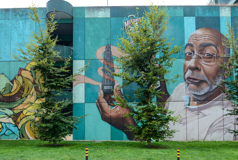 Porto Sehenswürdigkeiten: Eine große bemalte Wand Auf der ein Gesicht von einem Mann zu sehen ist der Einen Baum in der Hand hält.