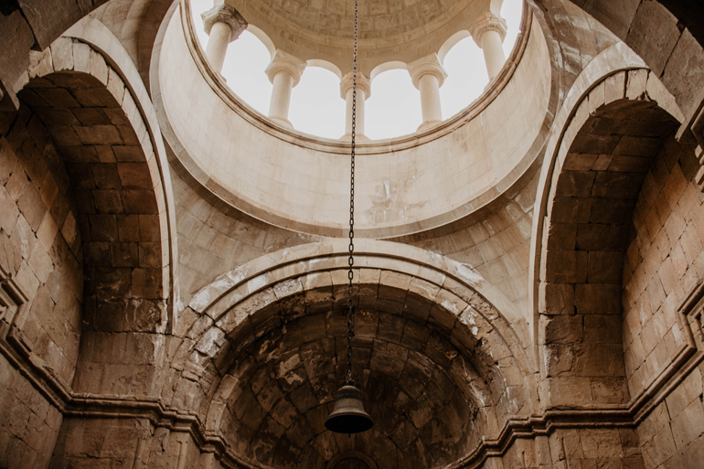 Die Kuppel einer Kirche von innen mit einer Glocke in der Mitte.