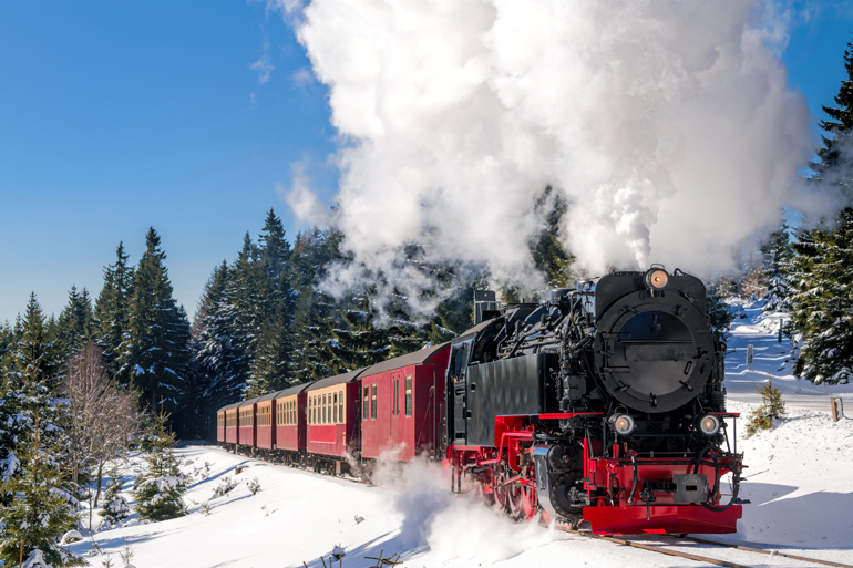 Die Brockenbahn, ein historischer Dampfzug, fährt durch eine Schneelandschaft auf den Berg Brocken im Gebirge Harz von Niedersachsen.
