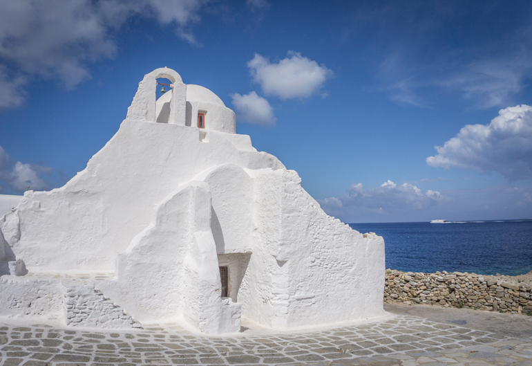 Eine weiße Kirche mit dem Meer im Hintergrund.
