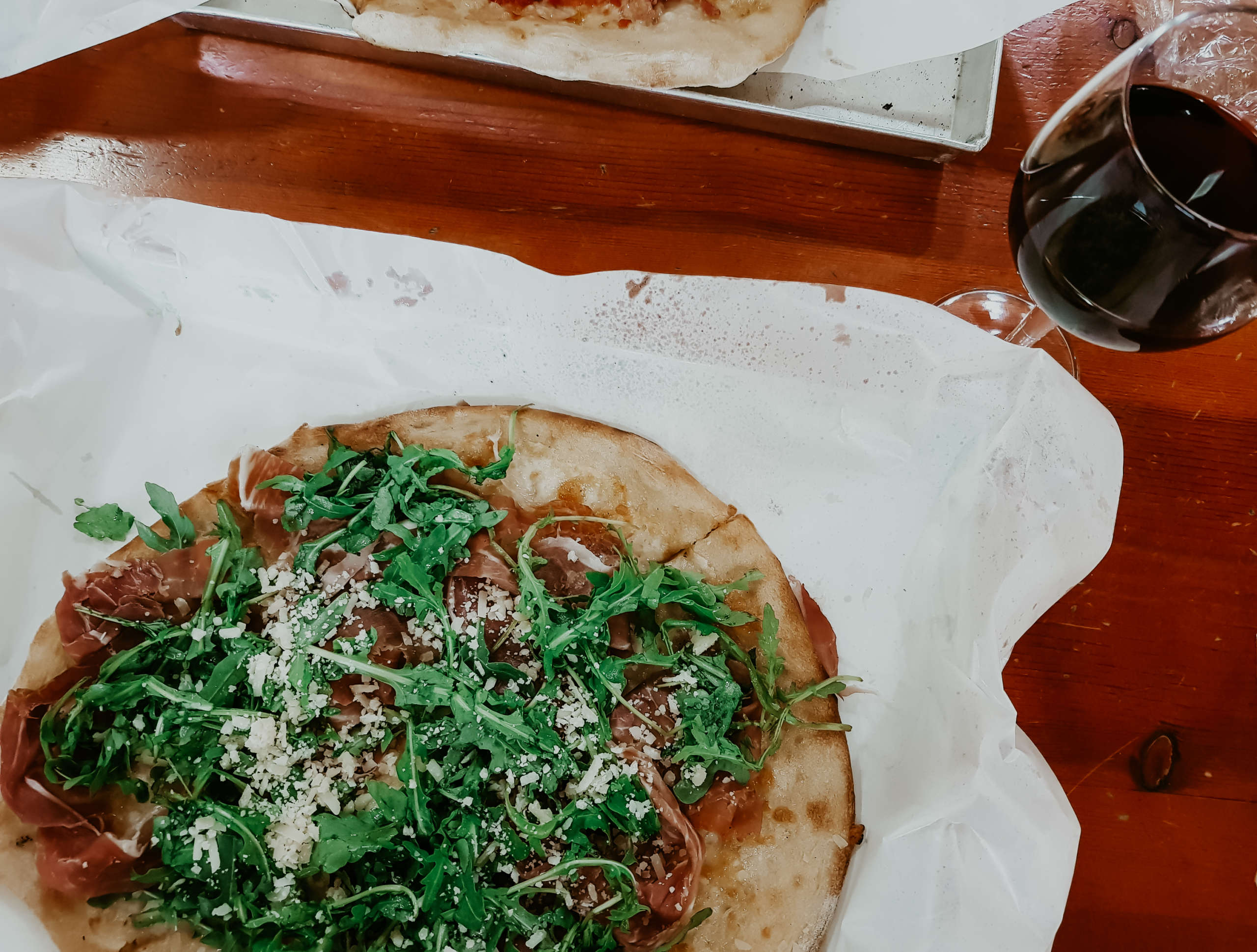 Eine Pizza mit einem Glas Rotwein daneben.