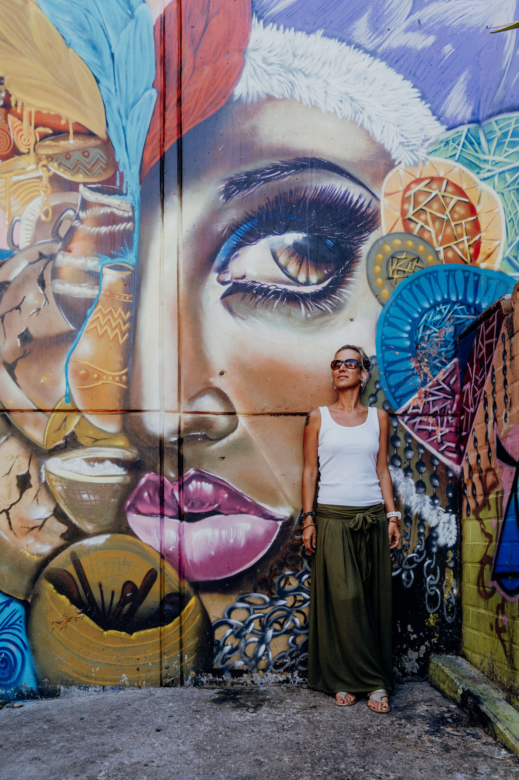 Violence once reigned in Comuna 13 – today it is art. A woman standing in front of a wall on which a head is marked.