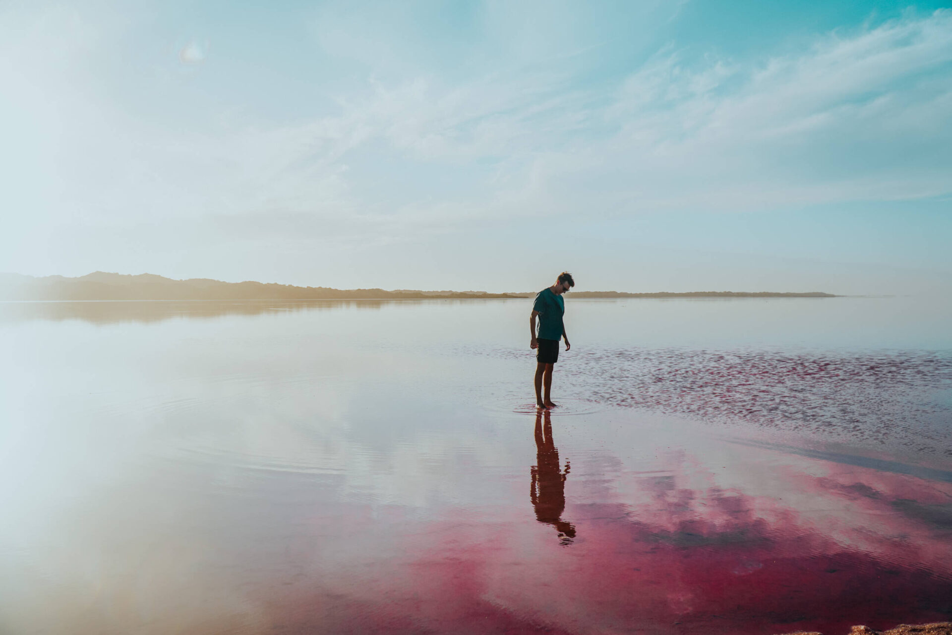 Ein Mann steht im Wasser und schaut sich die lila Wasseroberfläche an