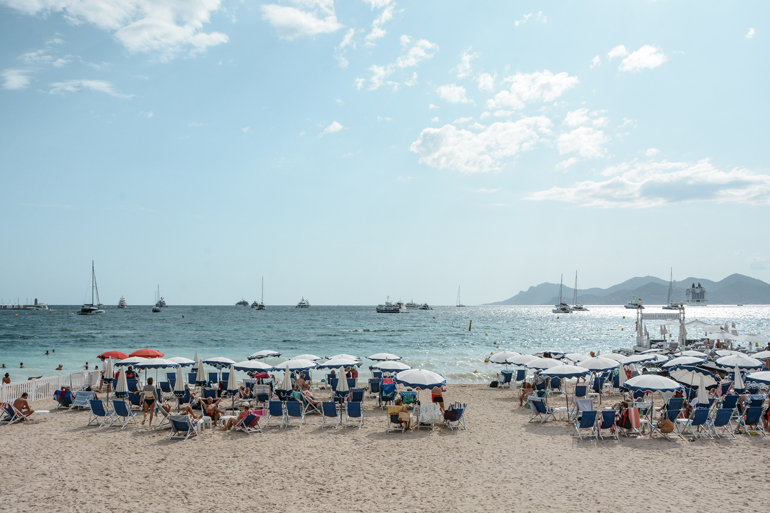 Ein Strand mit Liegestühlen und Sonnenschiermen.