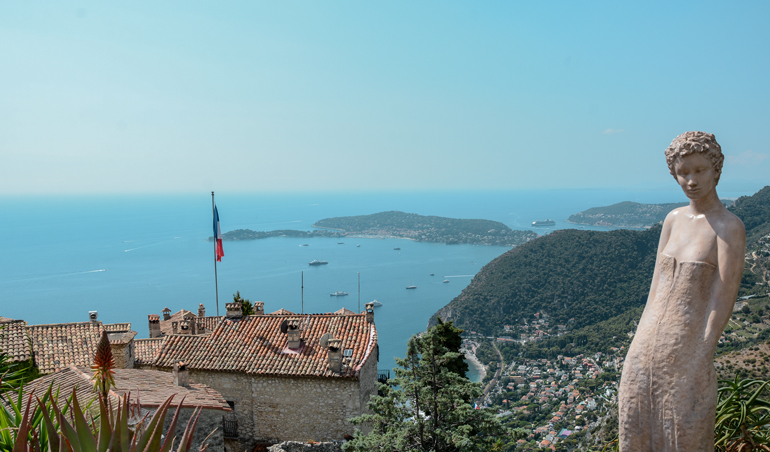 Eine Statue die auf einem Berg steht und das Meer im Hintergrund ist.