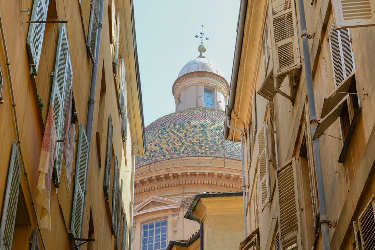 Eine Gasse mit Häusern und einem Kirchen Dom.