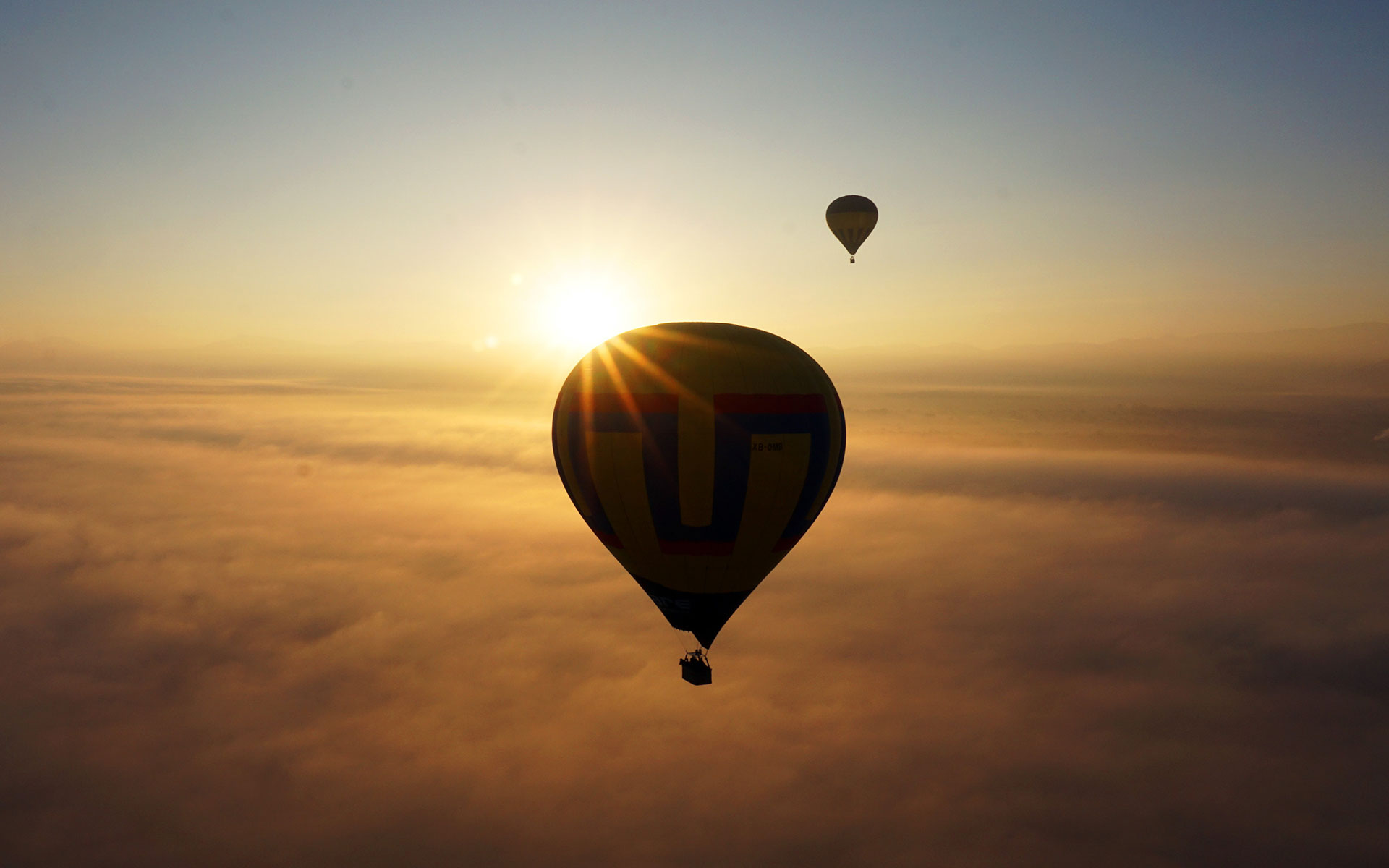 Ein Heißluftballon fliegt über den Wolken von Mexiko, genauer gesagt über den Pyramiden von Teotihuacán in die Abendsonne.