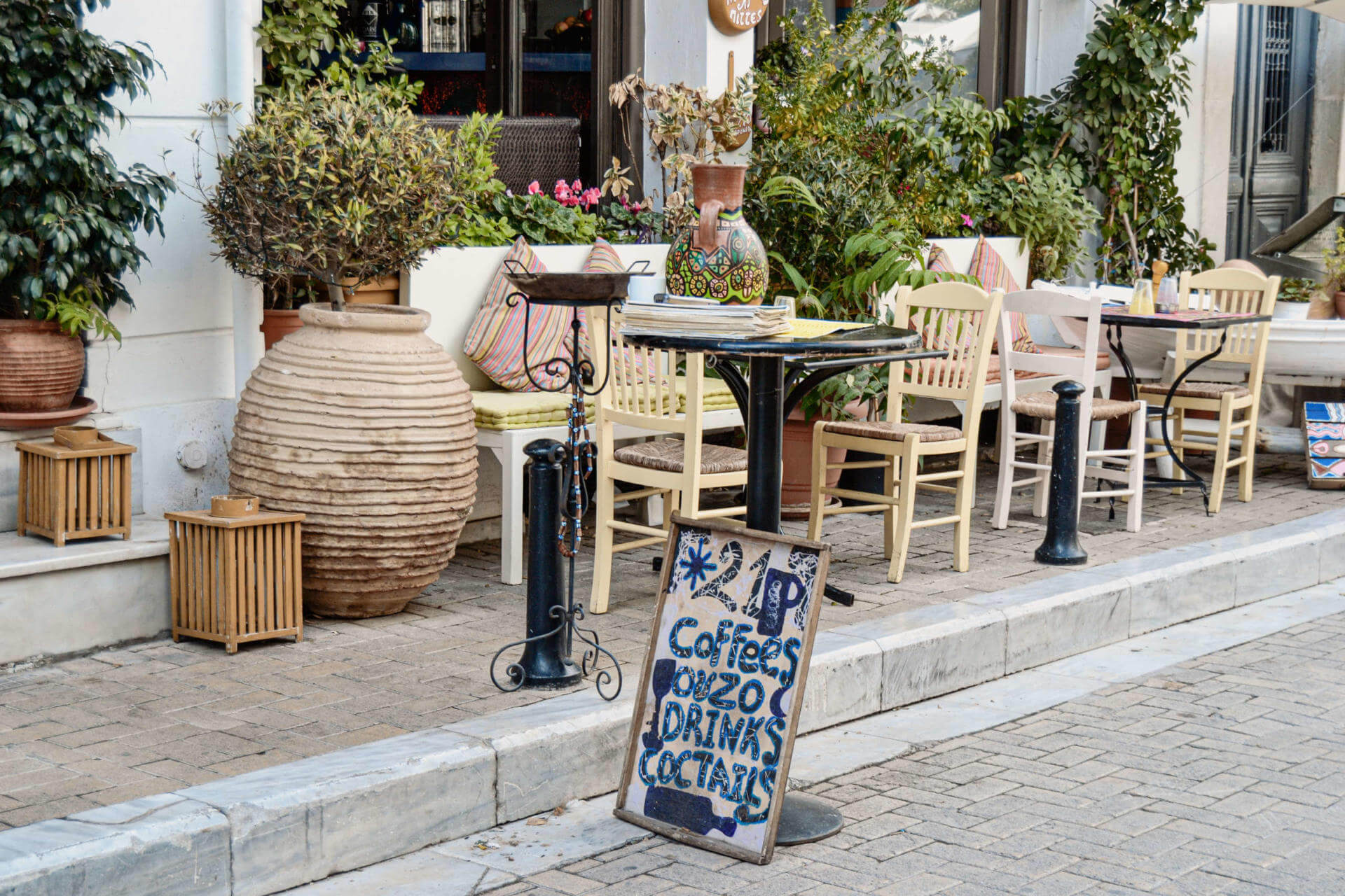 Außenterrasse eines Cafés in Athen im Stadtteil Plaka mit einladenden kleinen Stühlen und Tischen.
