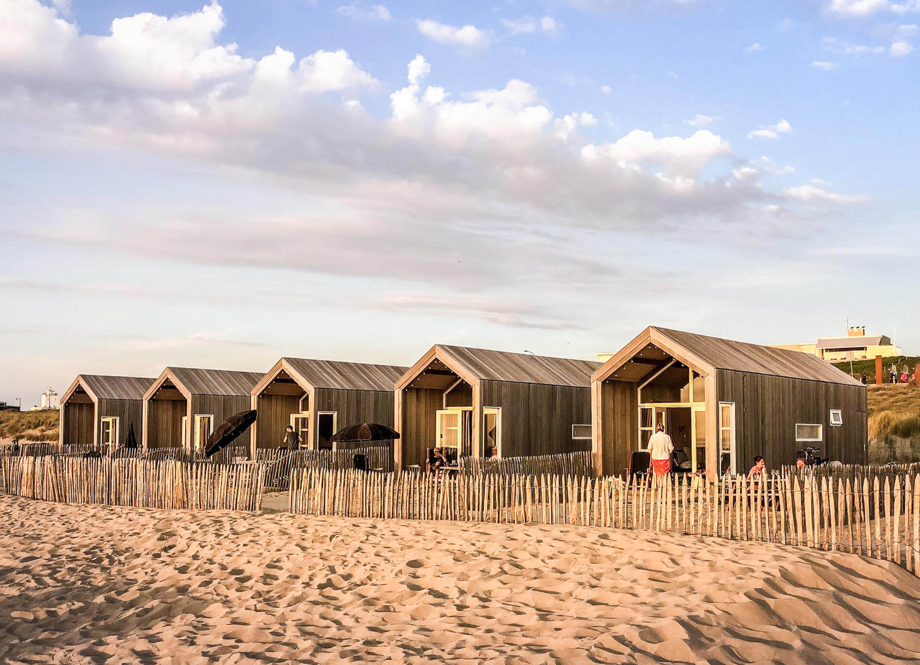 Sandstrand und fünf gleichaussehende Strandhäuser aus Holz nebeneinander in Katwik aan Zee in den Niederlanden