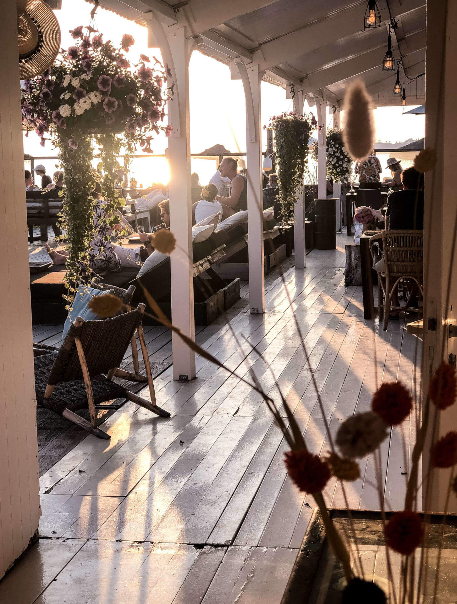 Blick von der Terrasse eines Strandpavillions in den Niederlanden auf die Sonnenterrasse, die mit Menschen auf Sonnenliegen gefüllt ist
