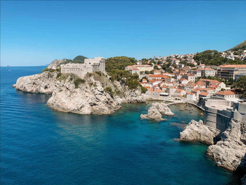 Ausblick auf das tiefblaue Meer der Adria und dahinter die am Hügel liegende Altstadt von Dubrovnik, Kroatien.
