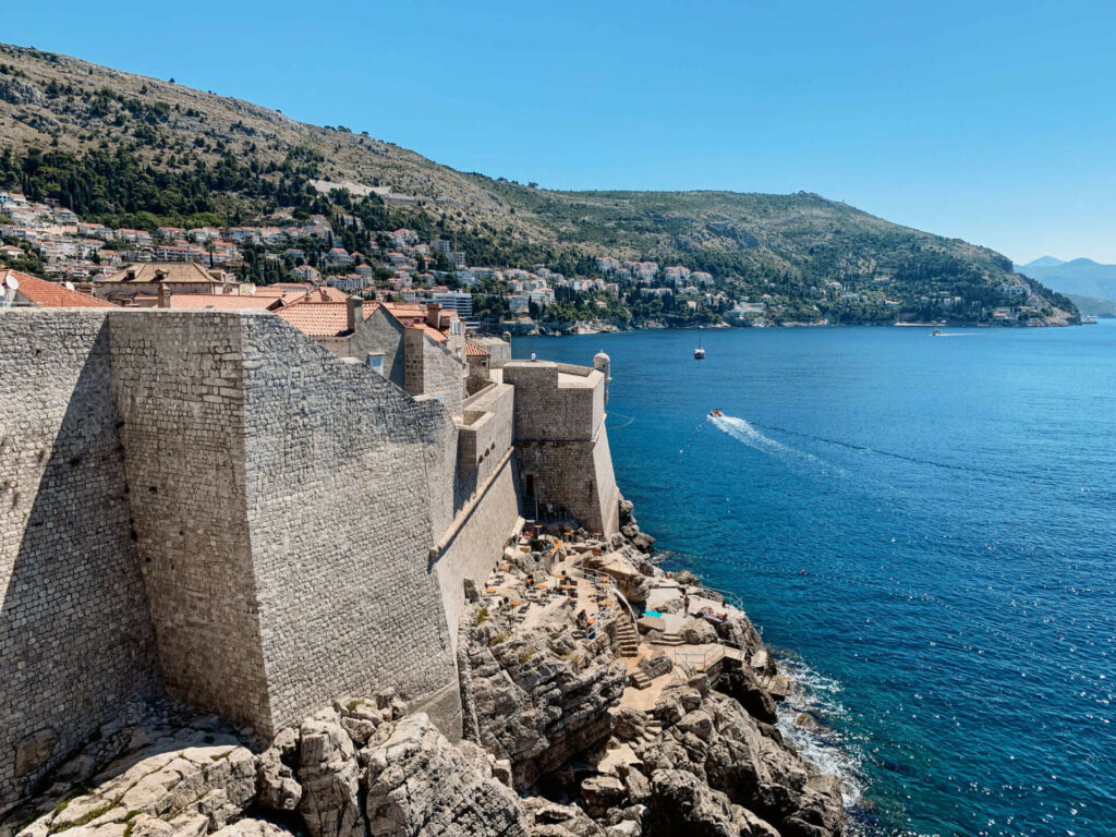 Vom Café Buža aus hat man einen traumhaften Blick auf die direkt an der Küste gebauten Festungsmauern von Dubrovnik, Kroatien.