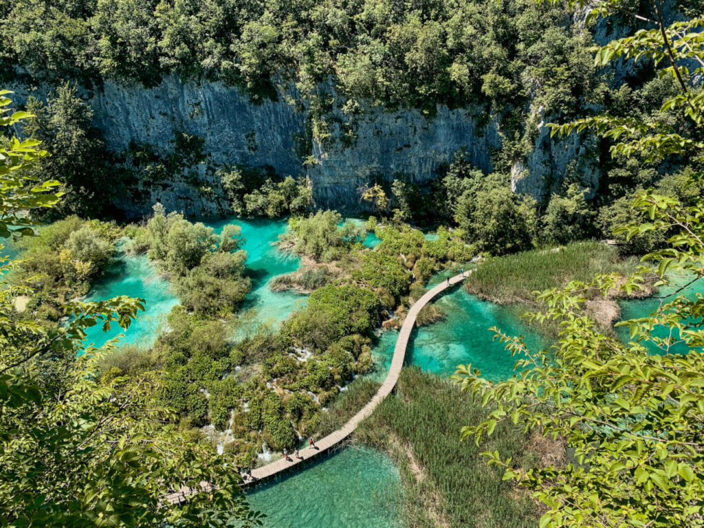 Hölzerne Wanderstege führen Besucher im Nationalpark Plitvicer Seen, Kroatien über das smaragdgrüne Wasser.