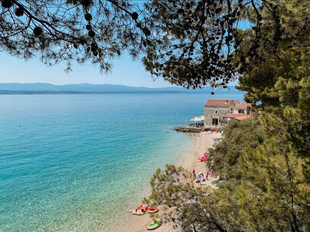 Blick von oben auf eine einladende Badebucht mit Sandstrand und türkisblauem Wasser an der Adria-Küste von Kroatien.