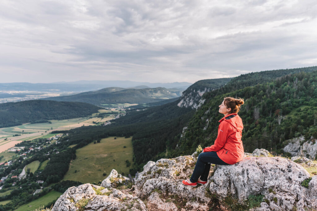 Bloggerin Melanie sitzt auf einem Felsenvorsprung im Naturpark Hohe Wand, der von Wien aus nur eine Stunde Autofahrt entfernt ist.