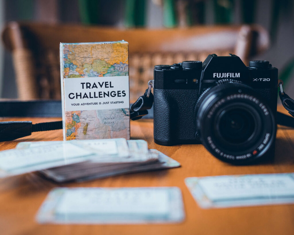 Damit wird es auf Reisen nicht langweilig: Ein Buch voller kleiner Karten, auf denen "Travel Challenges", also kleine zu bewältigende Aufgaben stehen, liegt einpackbereit neben der Kamera.