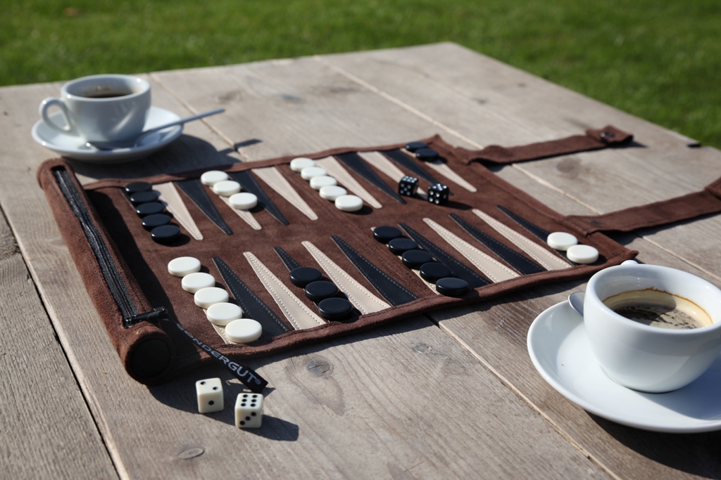 Für gemeinsame Spiele auf Reisen: Das Backgammon in einer leichten Ledertasche zum Aufrollen liegt auf dem Tisch ausgebreitet, die Spielsteine sind platziert.