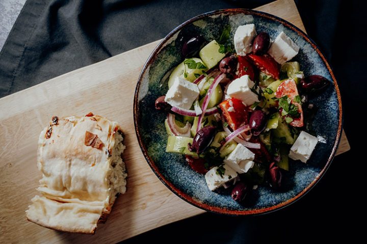 Die griechische Spezialität Tyropita, ein gefülltes Fladenbrot, mit Salat bestehend aus Feta, Oliven, Zwiebeln und Tomaten wird in Griechenland und weltweit gern zubereitet.