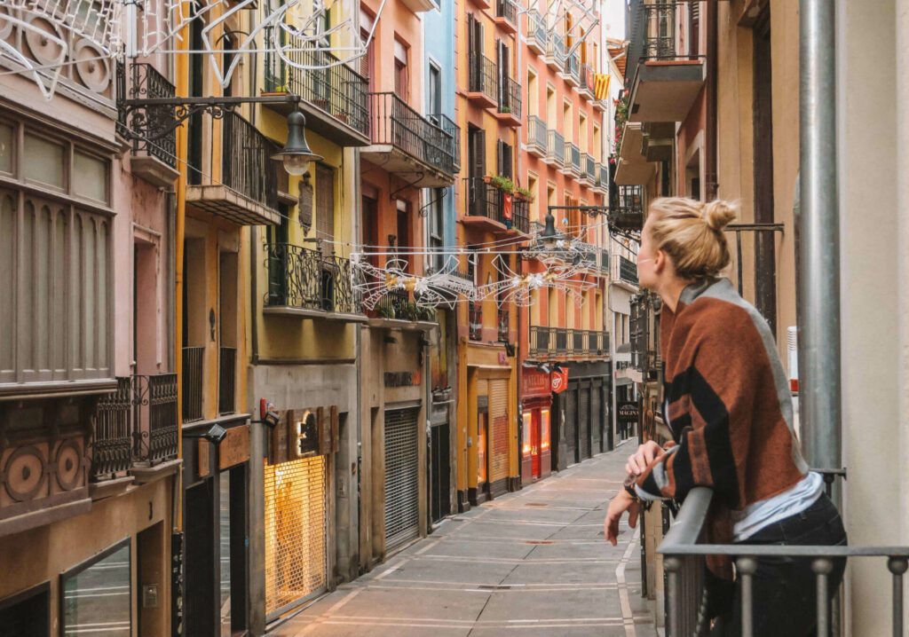 Travel blogger Nina enjoys the view from a small balcony in a narrow alleyway in the Spanish city of Pamplona.