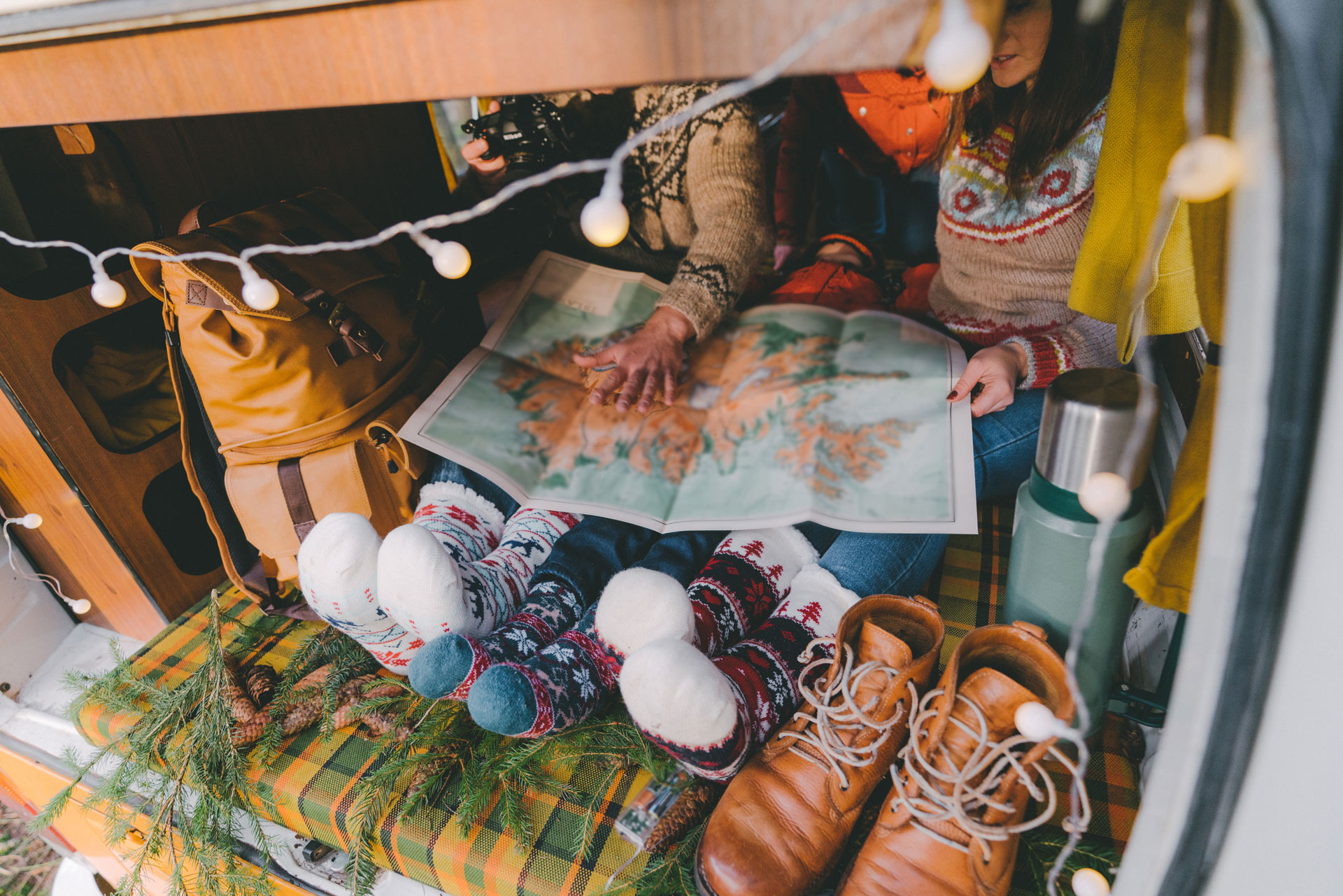 Eine Familie mit kleinem Kind sitzt in Weihnachtssocken im Campervan und plant auf einer Karte die Reise oder Reiseroute.