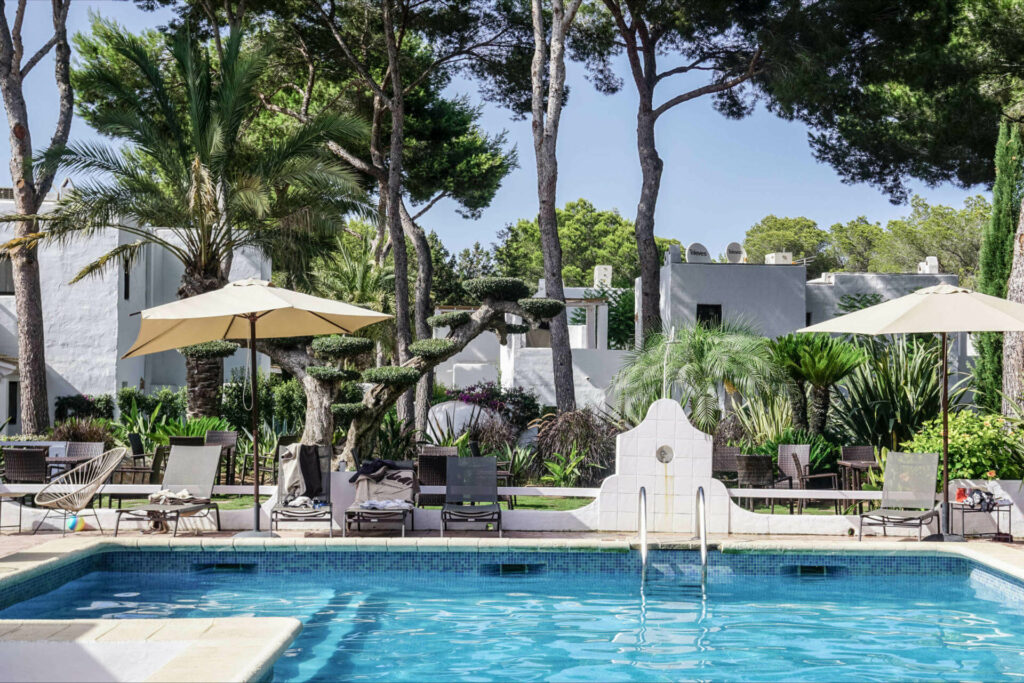 Im Pool der Unterkunft Hotel Casbah auf Formentera kann man zwischen Palmen und weißen Steingebäuden die Seele baumeln lassen.