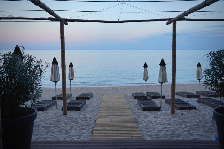 Der Sandstrand von Radjana Beach zum Sonnenaufgang mit Strandliegen und Sonnenschirmen - ein unbekannter Strand in Bulgarien.