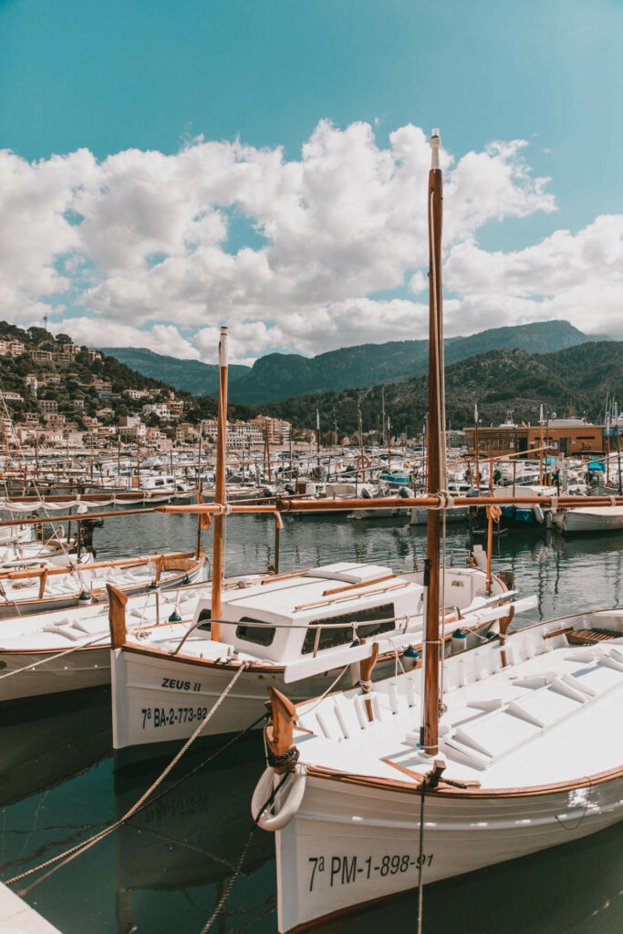 Einige Boote angedockt am Port de Sóller mit Bergen und Dörfern in der Ferne auf Mallorca.