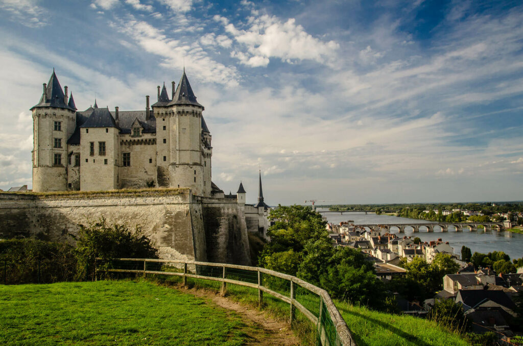 A castle towers over the village below by the river