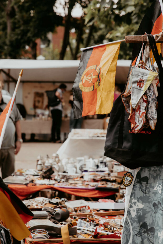 Ein Stand mit allerlei Gegenständen und alter DDR Fahne auf dem Mauerpark-Flohmarkt in Berlin.
