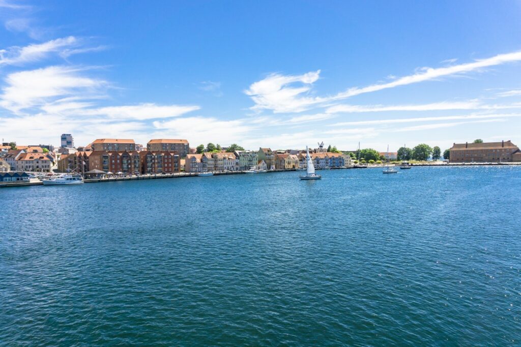 Über das tiefblaue Wasser hinweg sieht man die Uferpromenade von Sønderborg in Dänemark.