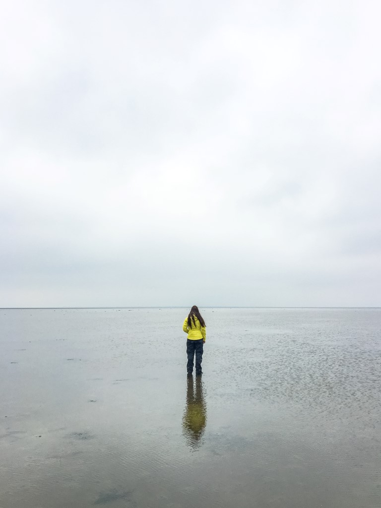 Biggi von den Phototravellers steht mit Regenausrüstung im Naturwunder Wattenmeer von Dänemark.