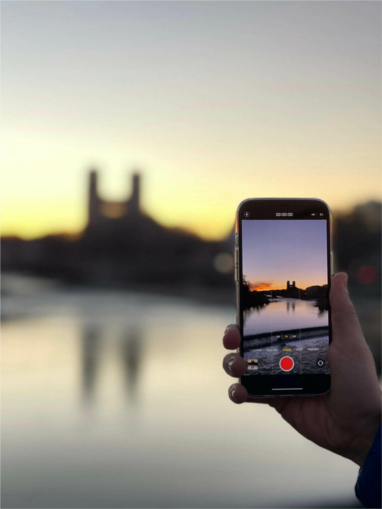 Reisefotografie ohne viel Kameraausrüstung: Die Video-Funktion auf einem Smartphone mit einer Abendkulisse in einer Stadt auf dem Display.