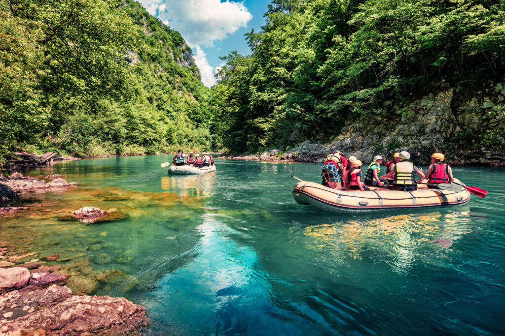 Eine Gruppe von Menschen macht einen Ausflug in Raftingbooten auf dem Tara Fluss
