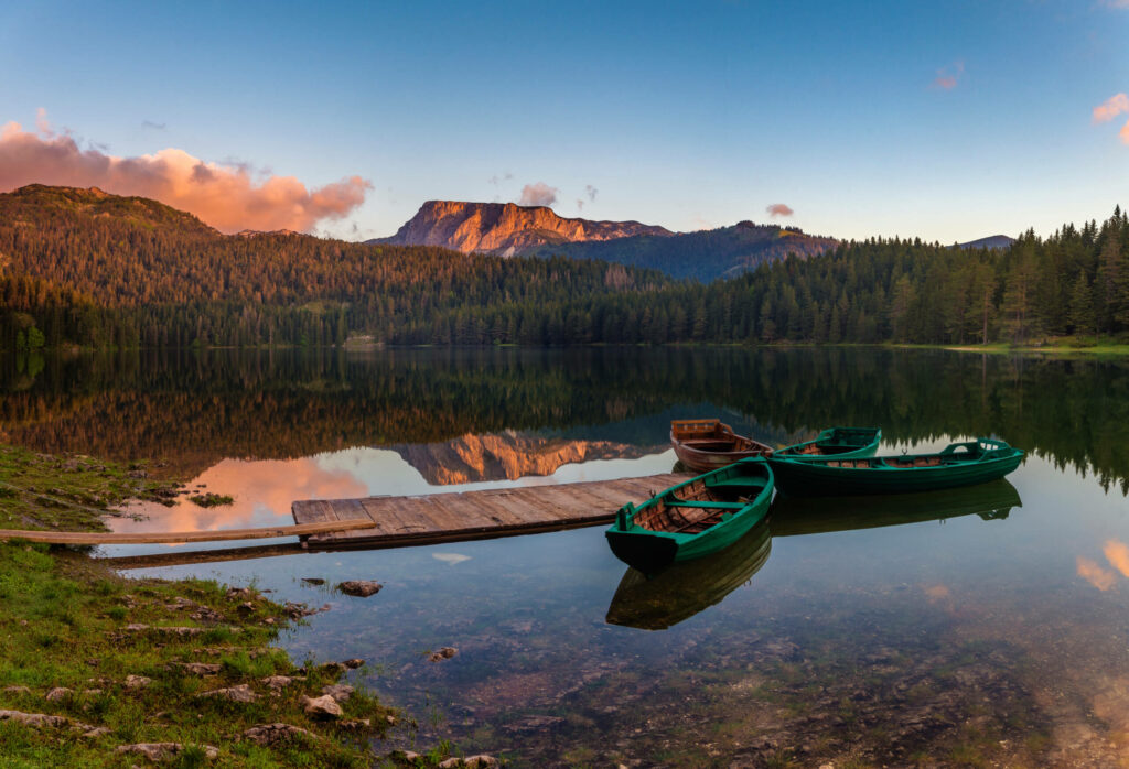 Die Sonne geht hinter den Bergen des Durmitor Nationalparks auf und spiegelt sich im See