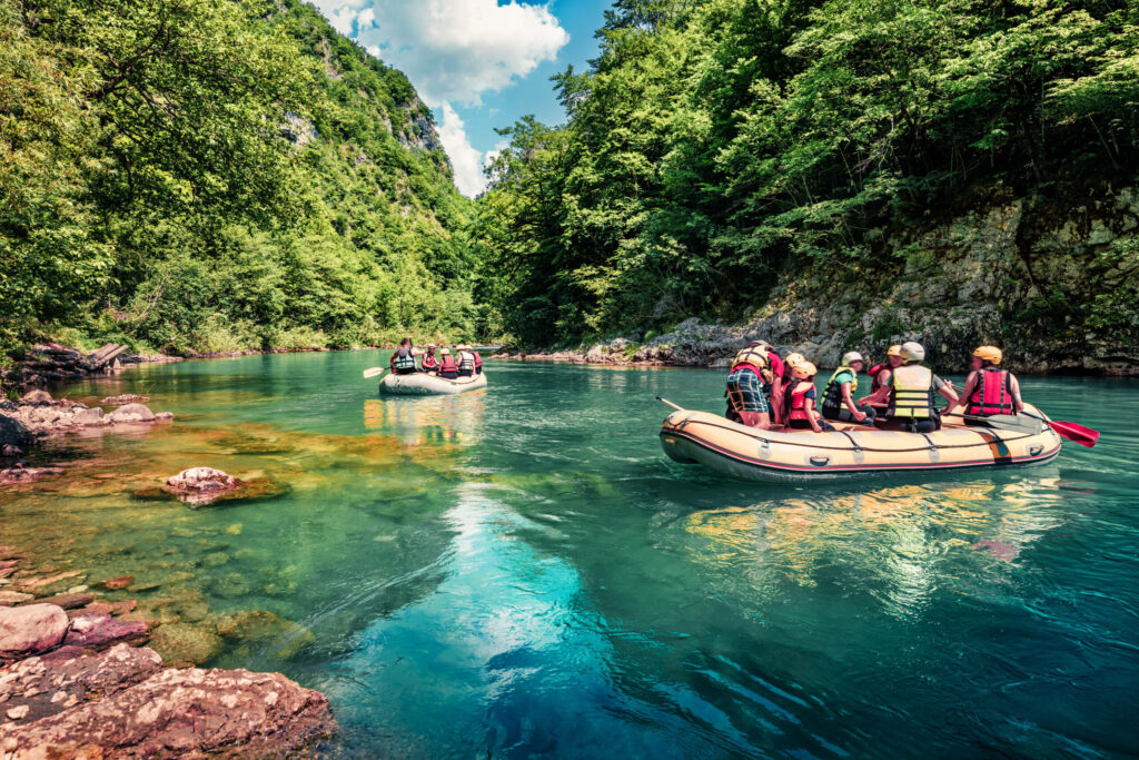 Eine Gruppe von Menschen macht einen Ausflug in Raftingbooten auf dem Tara Fluss