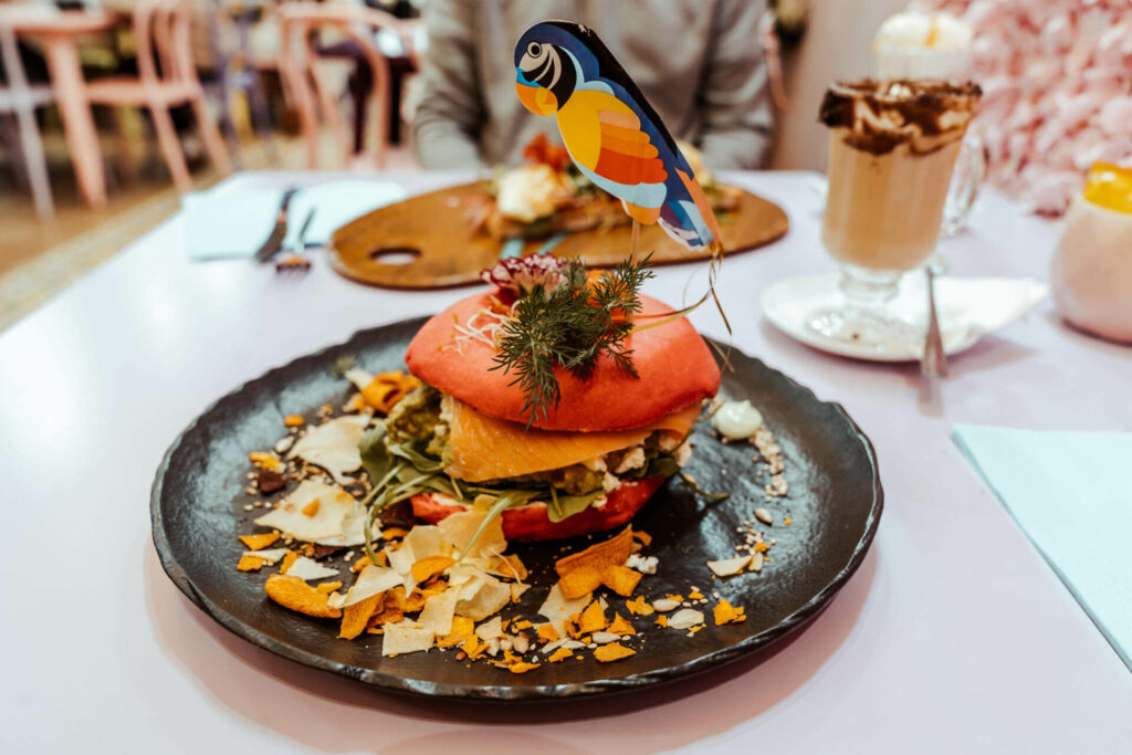 Bei der Eixampeling Brunch Café & Bar in Barcelona türmen sich beim The Smashed Avo Avocado, Feta, Rucola, Nüsse und auf Wunsch ein pochiertes Ei auf einem Red Velvet Bagel.